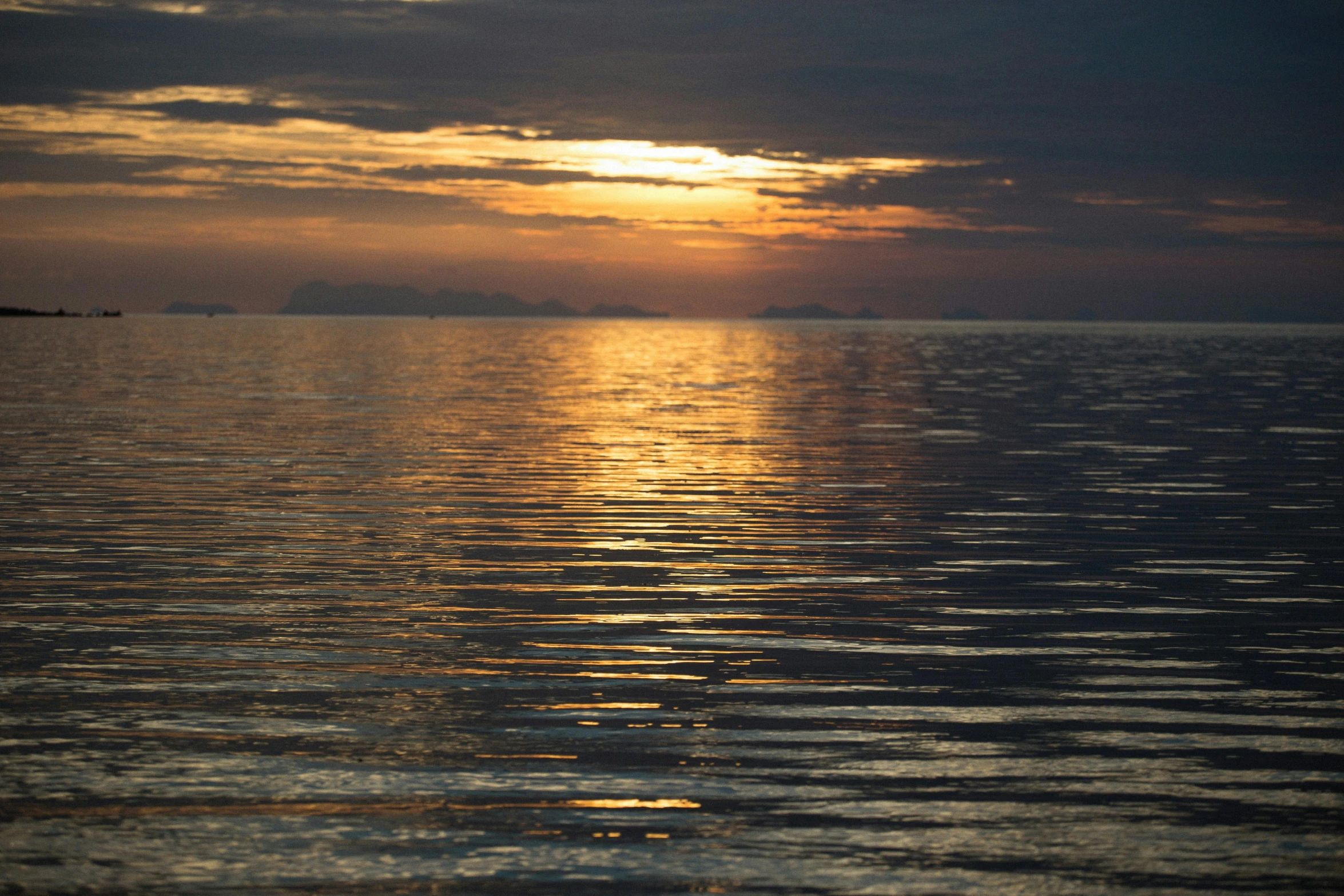 a sunset over the ocean with clouds reflecting in the water