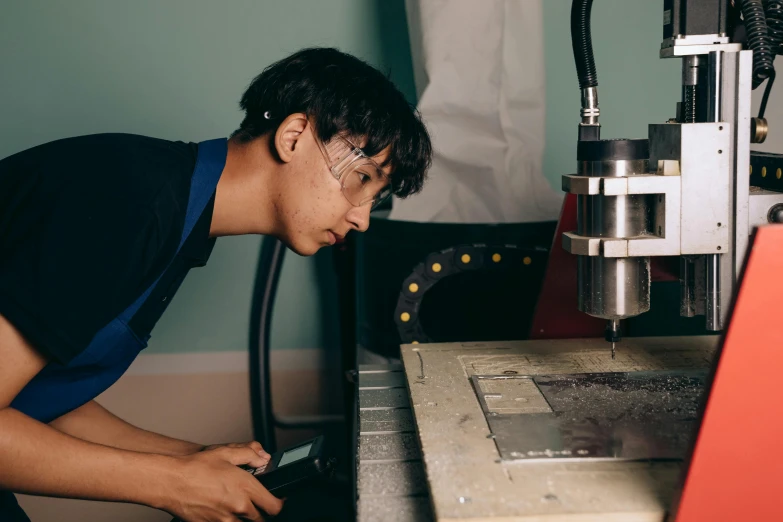 a man working on a machine in a room, pexels contest winner, profile image, teenage boy, asian male, looking serious