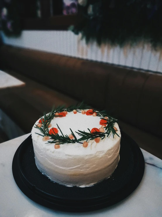 a white cake sitting on top of a black plate, trending on unsplash, renaissance, has a laurel wreath, orange and white color scheme, vsco, holiday season