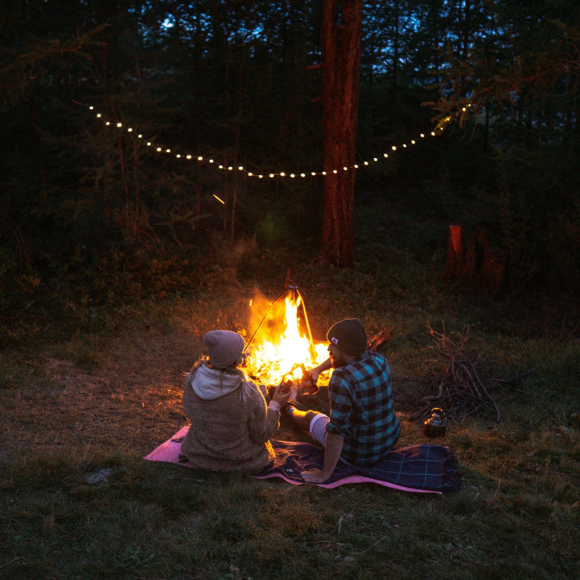 two people sitting around a campfire at night, by Jessie Algie, land art, mikko lagerstedt, summer setting, string lights, instagram post