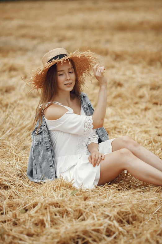 a girl sitting on a bed of dry grass