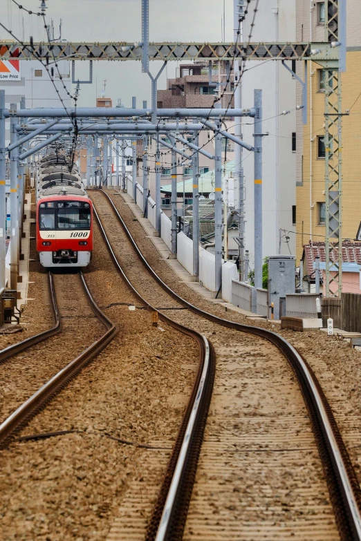a red and white train traveling down train tracks, shin hanga, golden raito, urban surroundings, connecting lines, sparsely populated