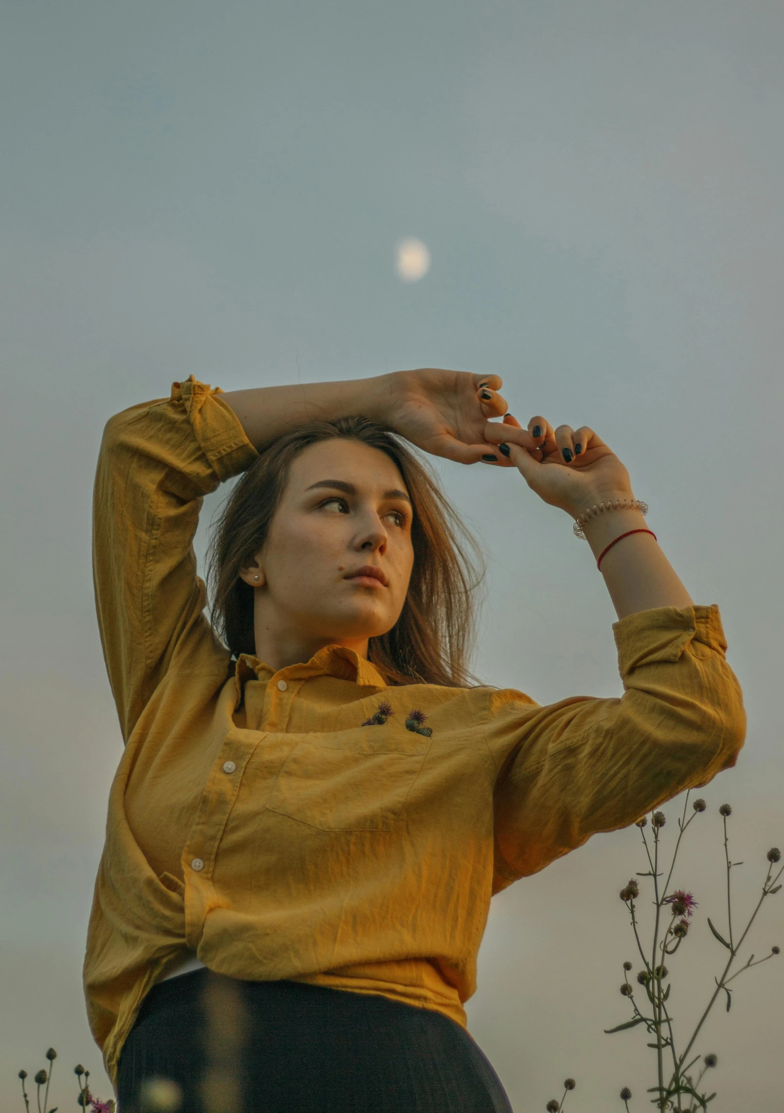 a woman in a yellow shirt standing in a field, an album cover, inspired by Elsa Bleda, pexels contest winner, in front of the moon, thoughtful pose, concert photo, androgynous person