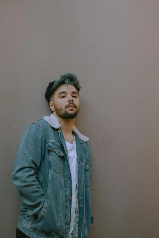 a man leans against a wall, looking to the side