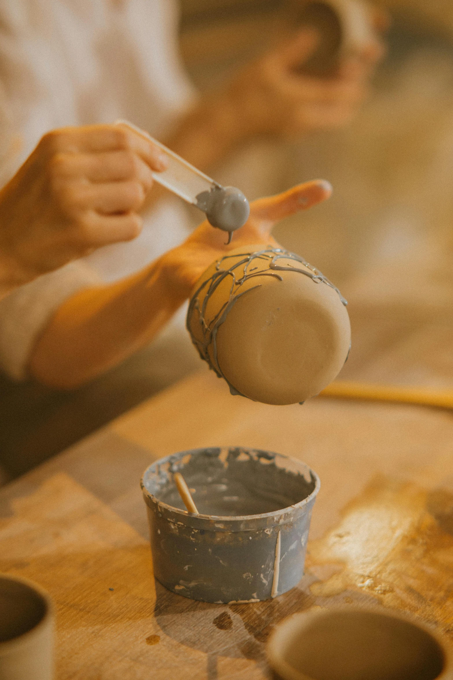 a person pouring something into a cup on a table, a picture, trending on pexels, arts and crafts movement, hard clay, facial, banner, studio quality product