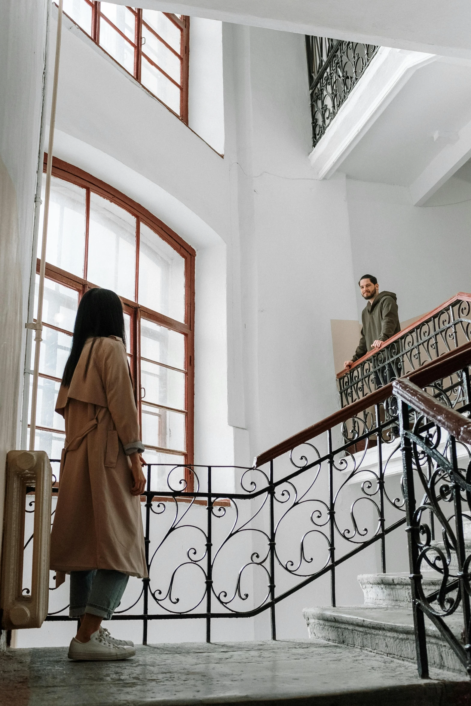 a couple of people that are standing on some stairs, high ceilings, woman is in a trenchcoat, 2019 trending photo, apartment