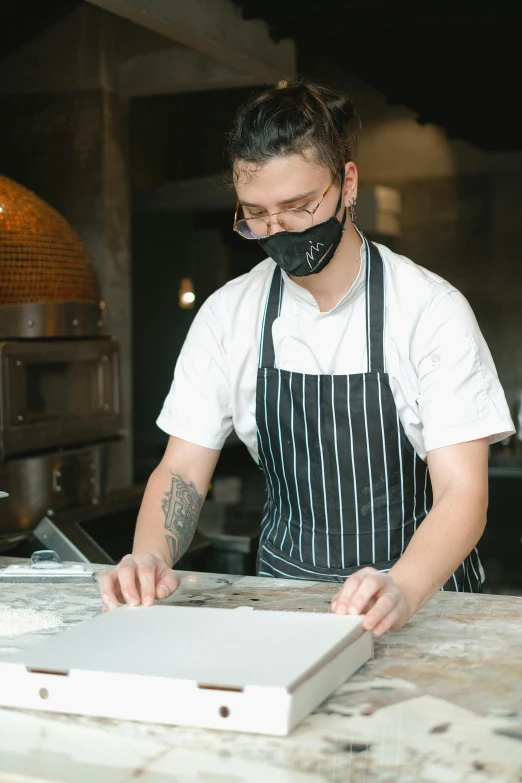 a man wearing a face mask working in a kitchen, inspired by Richmond Barthé, woodfired, flattened, pastry, smooth marble surfaces