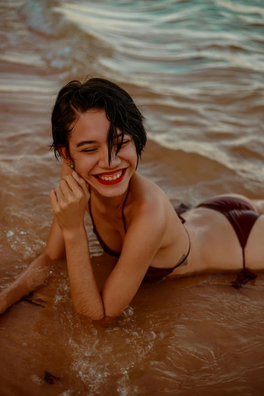 a woman laying on top of a sandy beach, inspired by Elsa Bleda, pexels contest winner, flirting smiling, wet look, young asian woman, wavy short hair