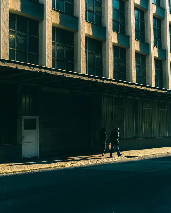 two people stand on a corner next to an empty sidewalk