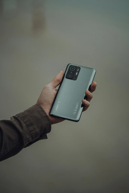 a person holding a cell phone in their hand, an album cover, by Matthias Stom, trending on pexels, realism, steel gray body, gradient green black, android cameraphone, 2 5 6 x 2 5 6