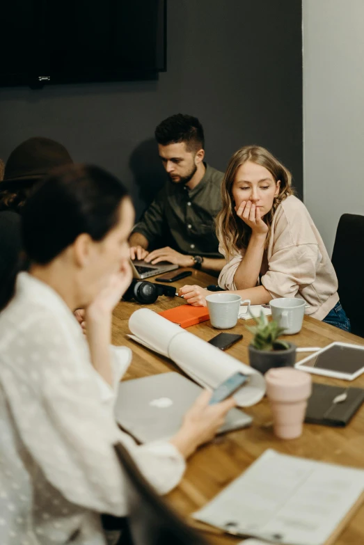 a group of people sitting around a wooden table, trending on pexels, happening, looking exhausted, developers, woman, thumbnail