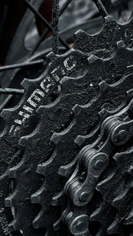 a close up of a bicycle chain on a bike, an album cover, by Emanuel Witz, unsplash, black textured, gears, full borg hyper detailed, mining