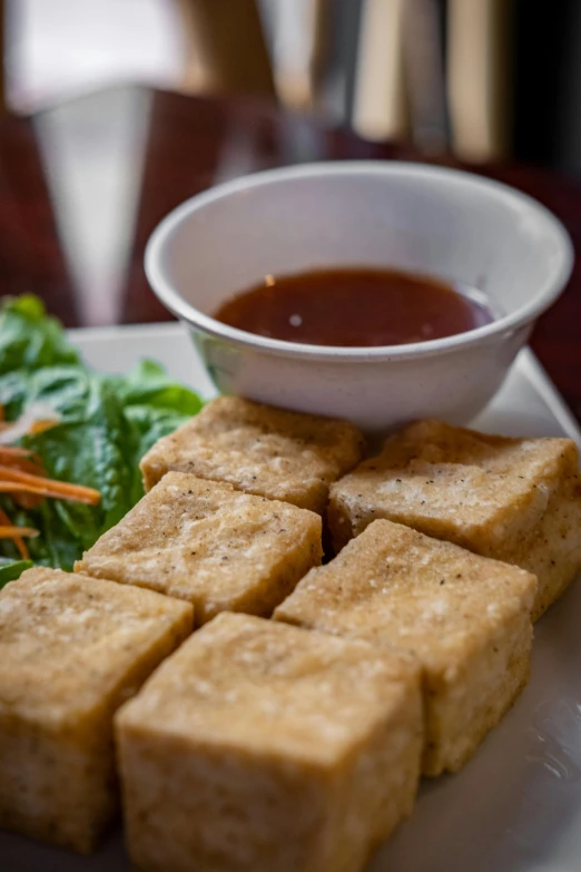 a white plate topped with tofu and green salad