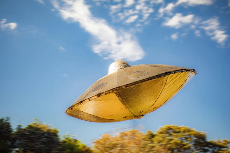 a yellow umbrella flying through a blue sky, unsplash, retrofuturism, derelict space ship, in australia, ufo in a forest, brown