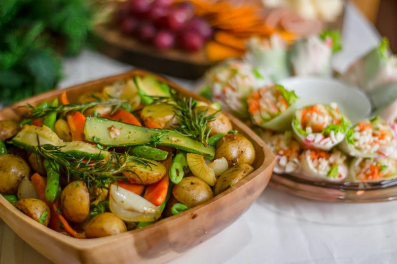 a wooden bowl filled with vegetables on top of a table, offering a plate of food, hot food, veggies, midsummer