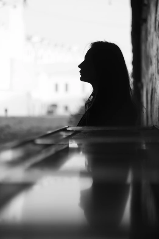 a black and white photo of a woman sitting at a table, a black and white photo, by Alexis Grimou, pexels contest winner, silhouette :7, pianist, photo of the girl, waiting behind a wall