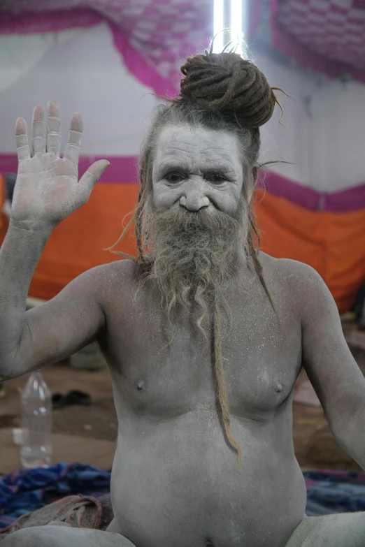 a man sitting on top of a bed covered in white paint, a cave painting, inspired by Kailash Chandra Meher, trending on reddit, very long white beard and hair, his palms are sweaty, loincloth, waving at the camera