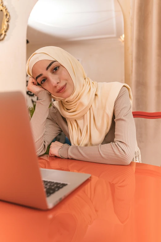 a woman sitting at a table with a laptop, inspired by Maryam Hashemi, hurufiyya, smug look, looking confident, orange, gen z