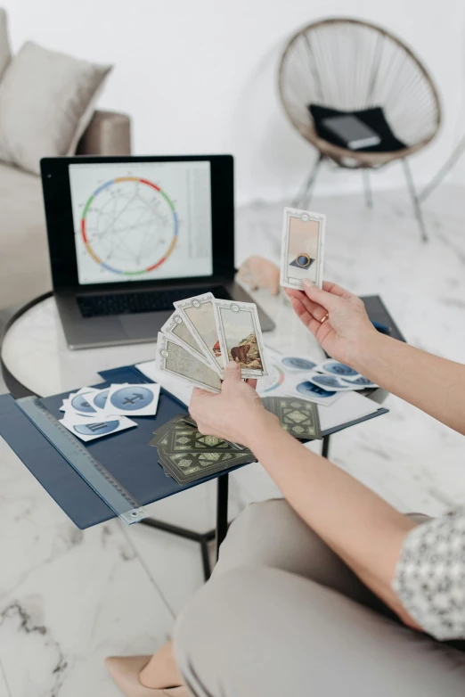 a woman sitting on a couch playing a video game, by Julia Pishtar, pexels contest winner, holography, tarot card layout, on a white table, pair of keycards on table, architect