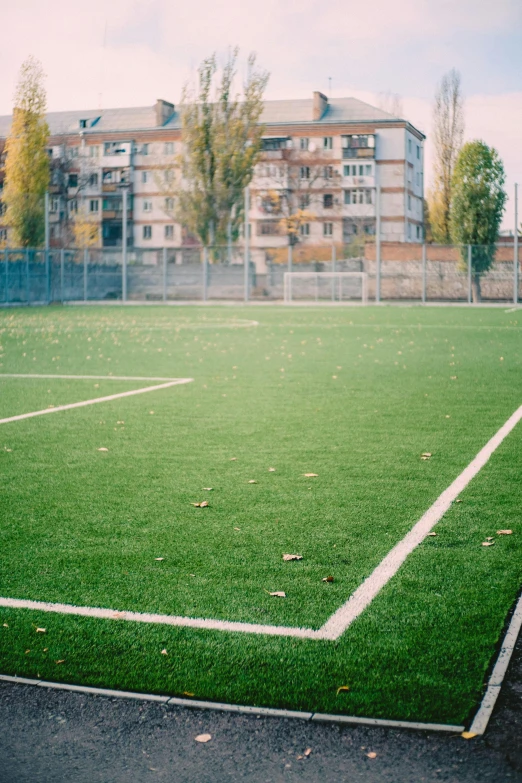 a soccer field with a building in the background, danube school, 15081959 21121991 01012000 4k, lo-fi, yellow carpeted, synthetic