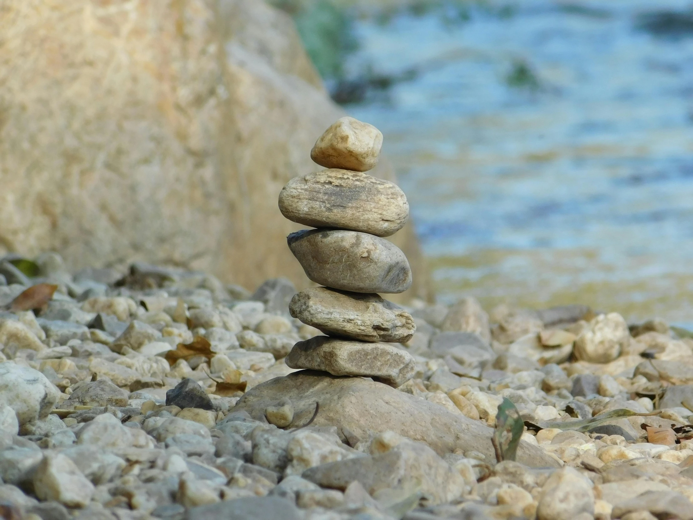 a stack of rocks sitting on top of a rocky beach, inspired by Andy Goldsworthy, unsplash, land art, next to a river, islamic, animation, outdoor photo