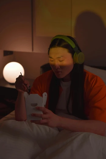 a woman sitting on top of a bed holding a cell phone, inspired by Liam Wong, video art, wearing gaming headset, eating ramen, mood light, worksafe. cinematic