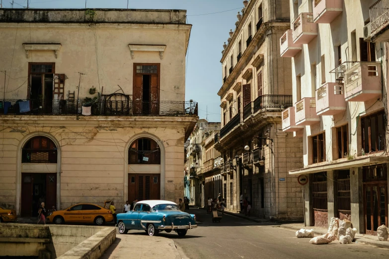 an old car is driving through a street lined with old buildings