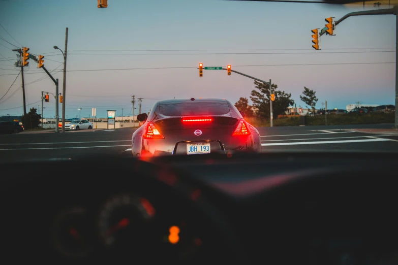 a car driving down a street next to traffic lights, by Matt Cavotta, pexels contest winner, in a modified nissan skyline r34, difraction from back light, car on highway, inside of a car