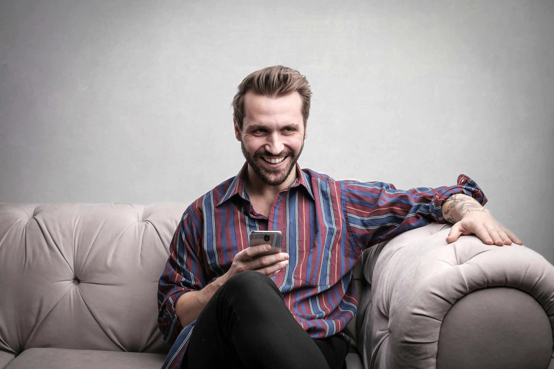 a man sitting on a couch holding a cellphone