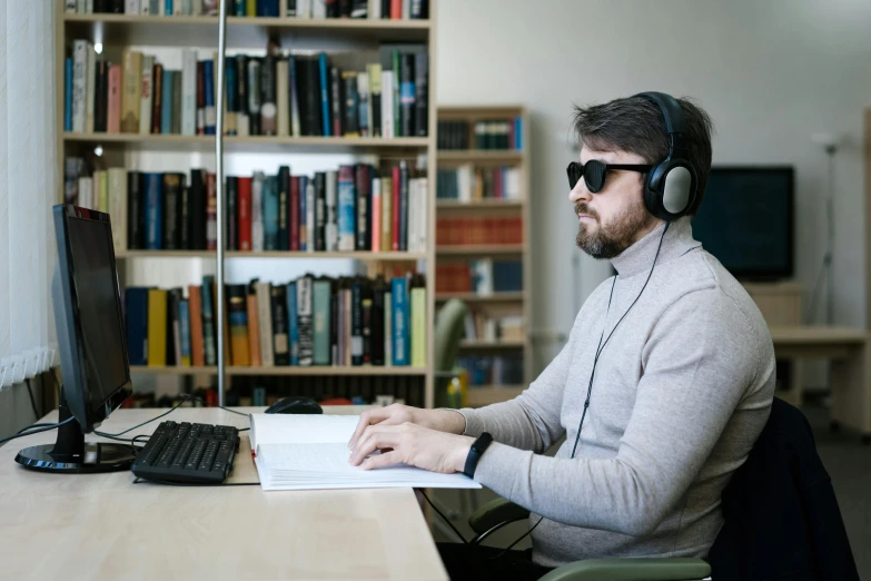 a man sitting at a desk in front of a computer, library nerd glasses, wearing modern headphone, hyperreal movie shot, image
