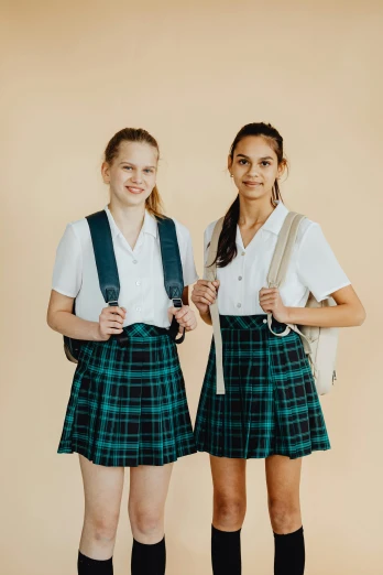 two girls in school uniforms standing next to each other, trending on unsplash, plain background, greens), tartan garment, manuka