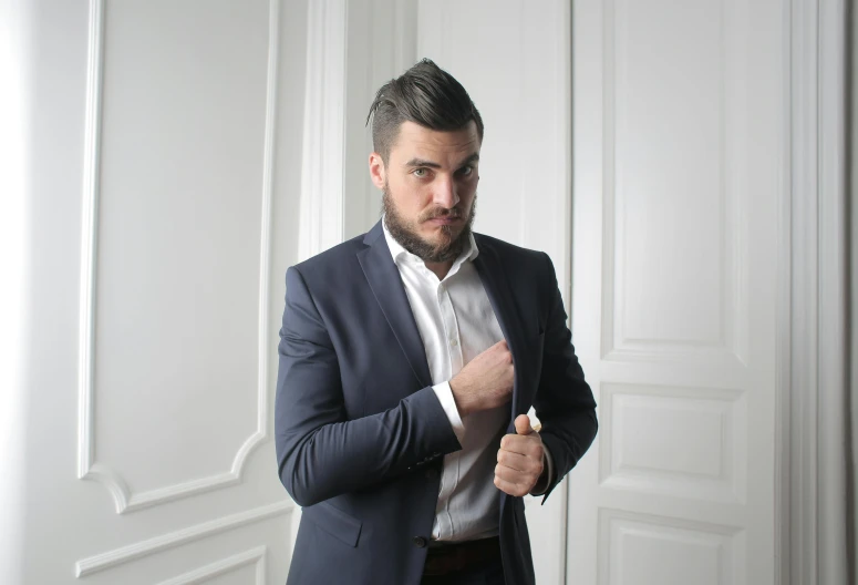 a man in a suit and tie fixes his jacket