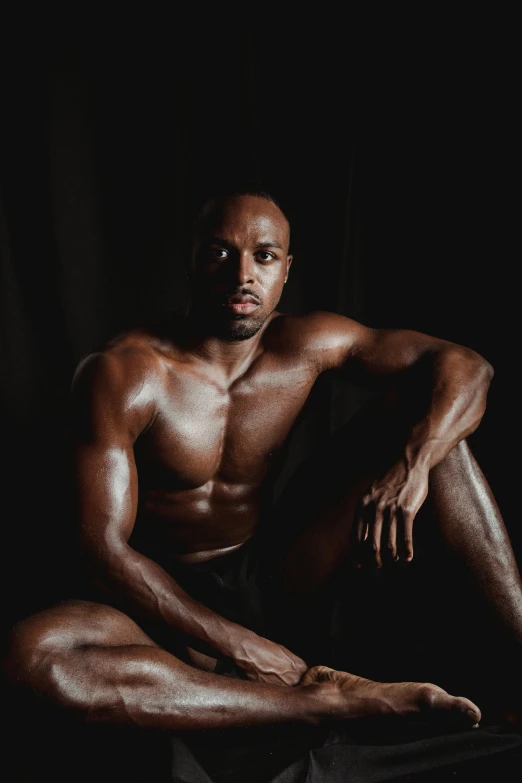 a man with  sitting on the ground in front of a black background