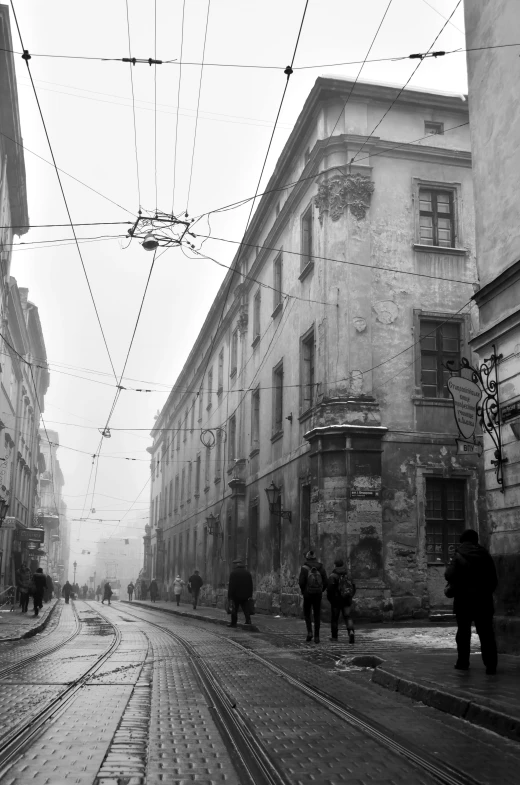 a black and white photo of a city street, inspired by Józef Pankiewicz, wires hanging above street, winter 1941, old library, view from the street