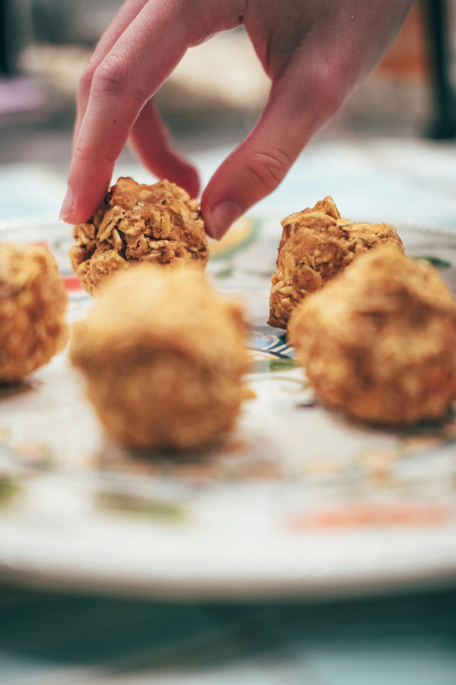 a person reaching for some food on a plate, golden orbs, fried chicken, entertaining, up close