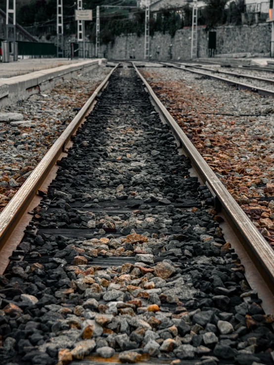 a close up of a train track near a building, with lots of dark grey rocks, intense knowledge, facing away, profile picture