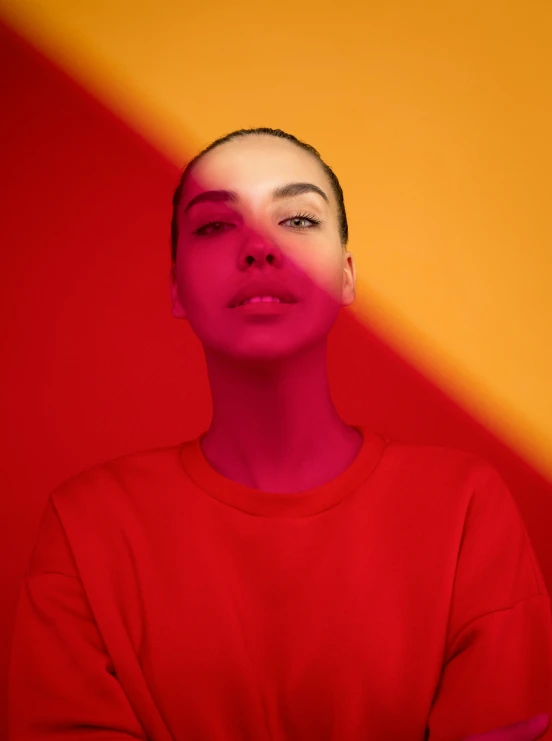 a woman standing in front of a red and yellow wall, an album cover, inspired by Elsa Bleda, trending on pexels, portrait of gal gadot, gradient red to yellow, red lighting on their faces, bisexual lighting