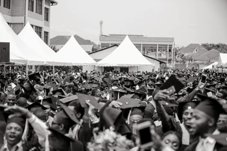 a black and white photo of a large crowd of graduates, by Nicolette Macnamara, pexels, adebanji alade, pastel', helmet view, blissful atmosphere