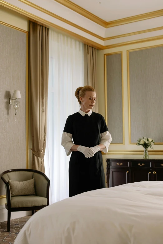 an older woman stands by a large bed