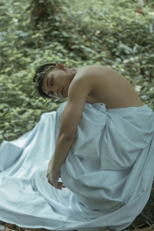 a woman in white cloth sitting down in the woods