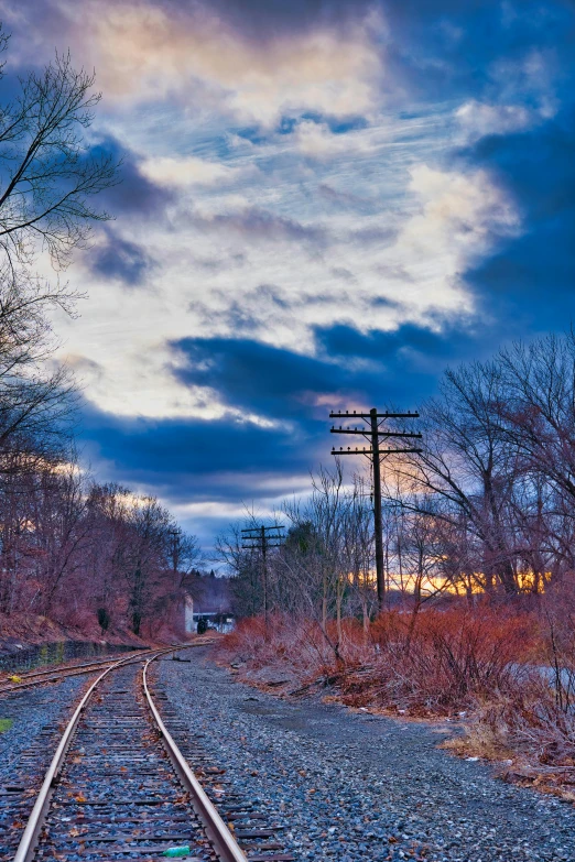 railroad tracks under cloudy skies at twilight on an abandoned road