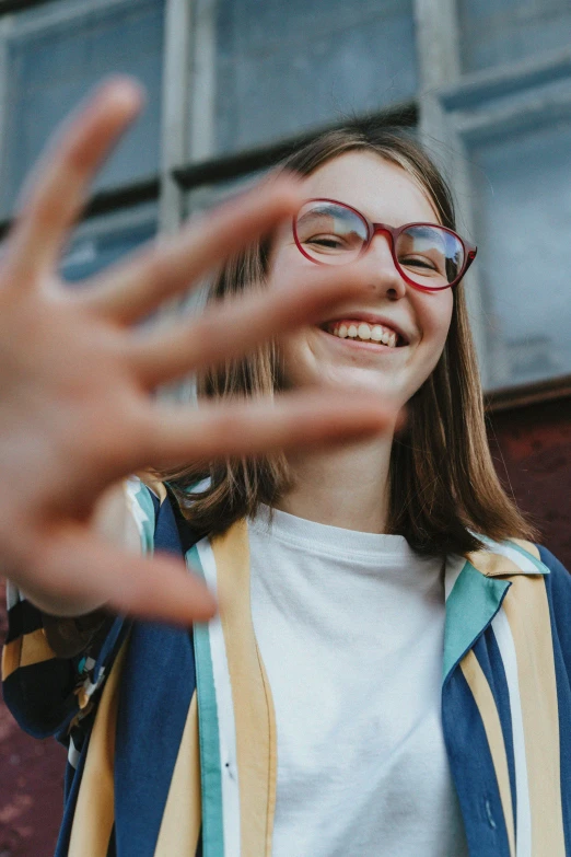 girl smiling and waving her hand while outside