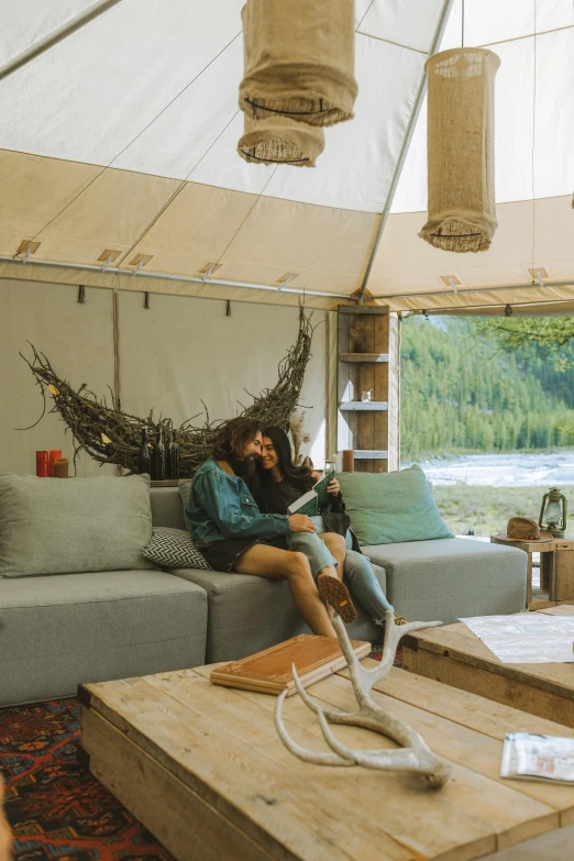 a man sitting on top of a couch in a living room, glamping, whistler, canopies, couple