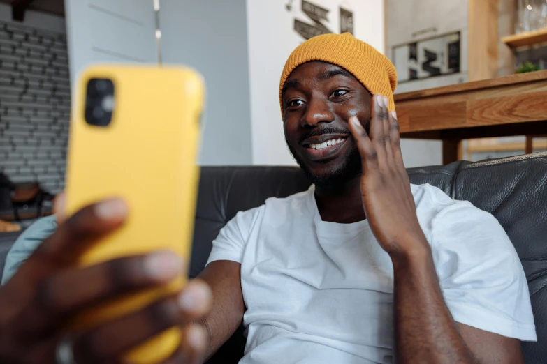 a man sitting on a couch holding a cell phone, a picture, trending on pexels, happening, with yellow cloths, african facial features, taking a selfie, youtube thumbnail