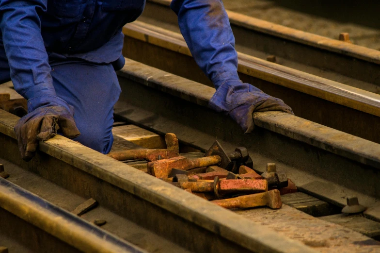 a man working on a rail road track, pexels contest winner, figuration libre, blue gloves, many rusty joints, 🦩🪐🐞👩🏻🦳, working in the forge