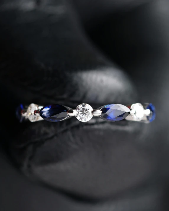 a close up of a ring on a shoe, midnight blue, silver and sapphire, 3 mm, on a dark background