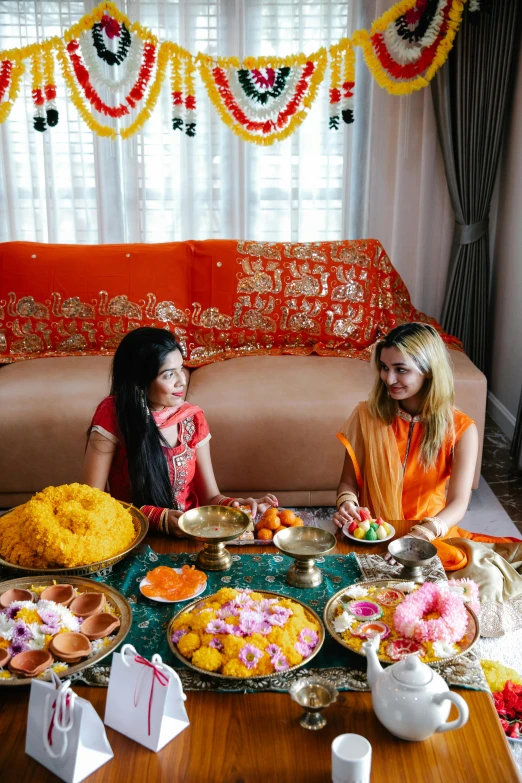 two women sitting at a table with plates of food