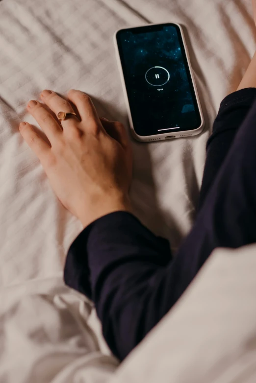 a person laying in bed with a cell phone, trending on pexels, wearing two metallic rings, connected to heart machines, wearing a dark shirt and jeans, wearing a simple robe