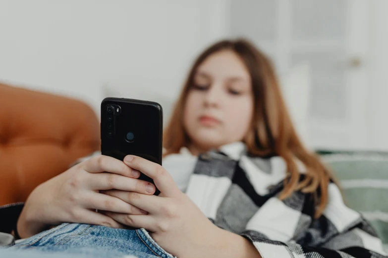 a woman sitting on a couch looking at her cell phone, by Adam Marczyński, trending on pexels, happening, portrait of teenage girl, flattened, avatar image, close-up photo