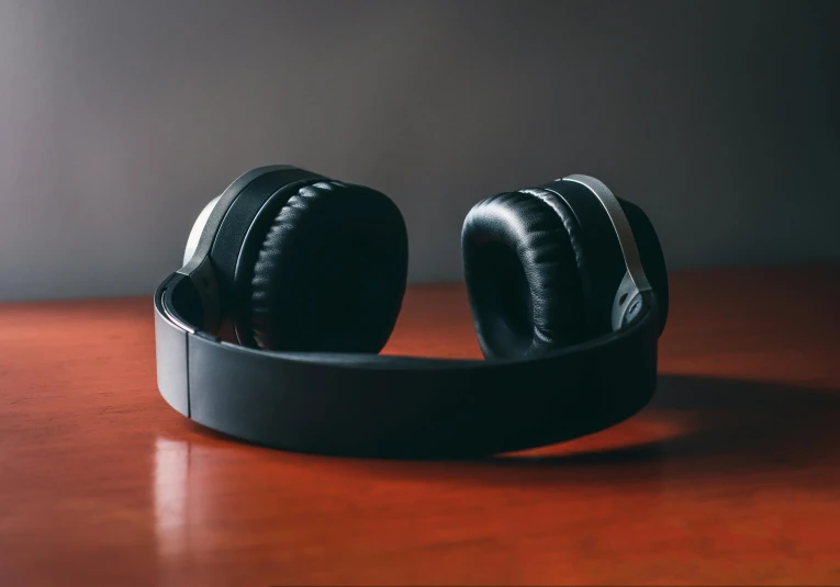 a pair of headphones sitting on top of a wooden table, pexels contest winner, hurufiyya, tones of black in background, over-shoulder shot, thumbnail, test